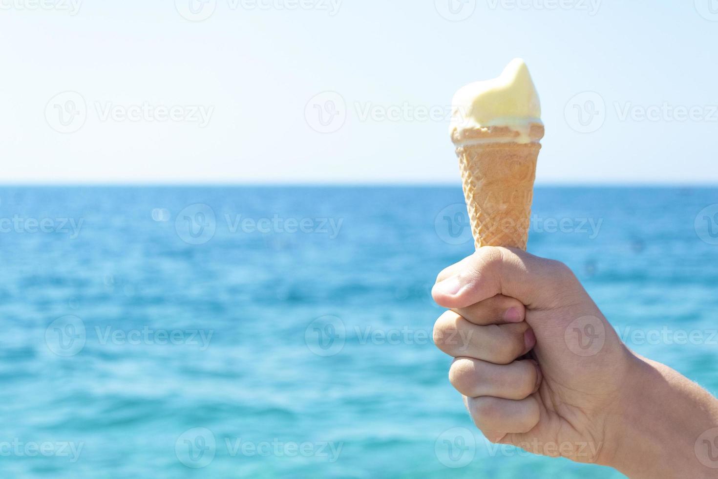 Child hand holding ice cream opposite blue sea 13418035 Stock Photo at