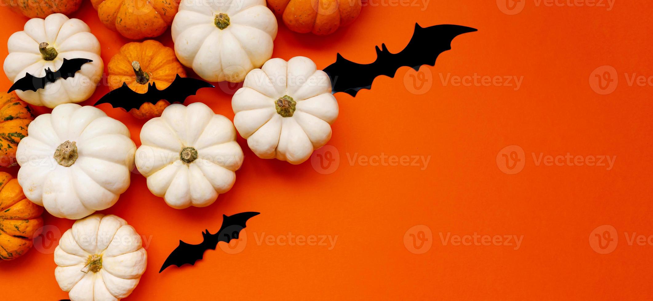 Halloween flat lay composition of black paper bats fand pumpkins on orange background. Halloween concept. photo