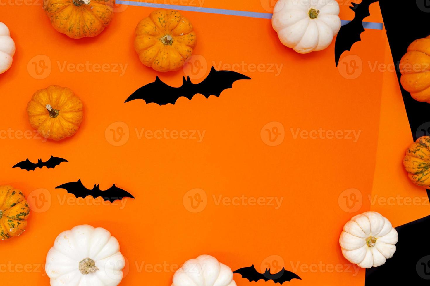 Halloween flat lay composition of black paper bats fand pumpkins on orange background. Halloween concept. photo
