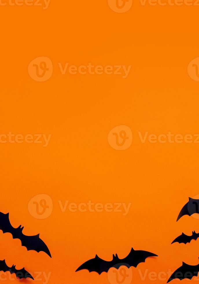 Halloween flat lay composition of black paper bats fand pumpkins on orange background. Halloween concept. photo