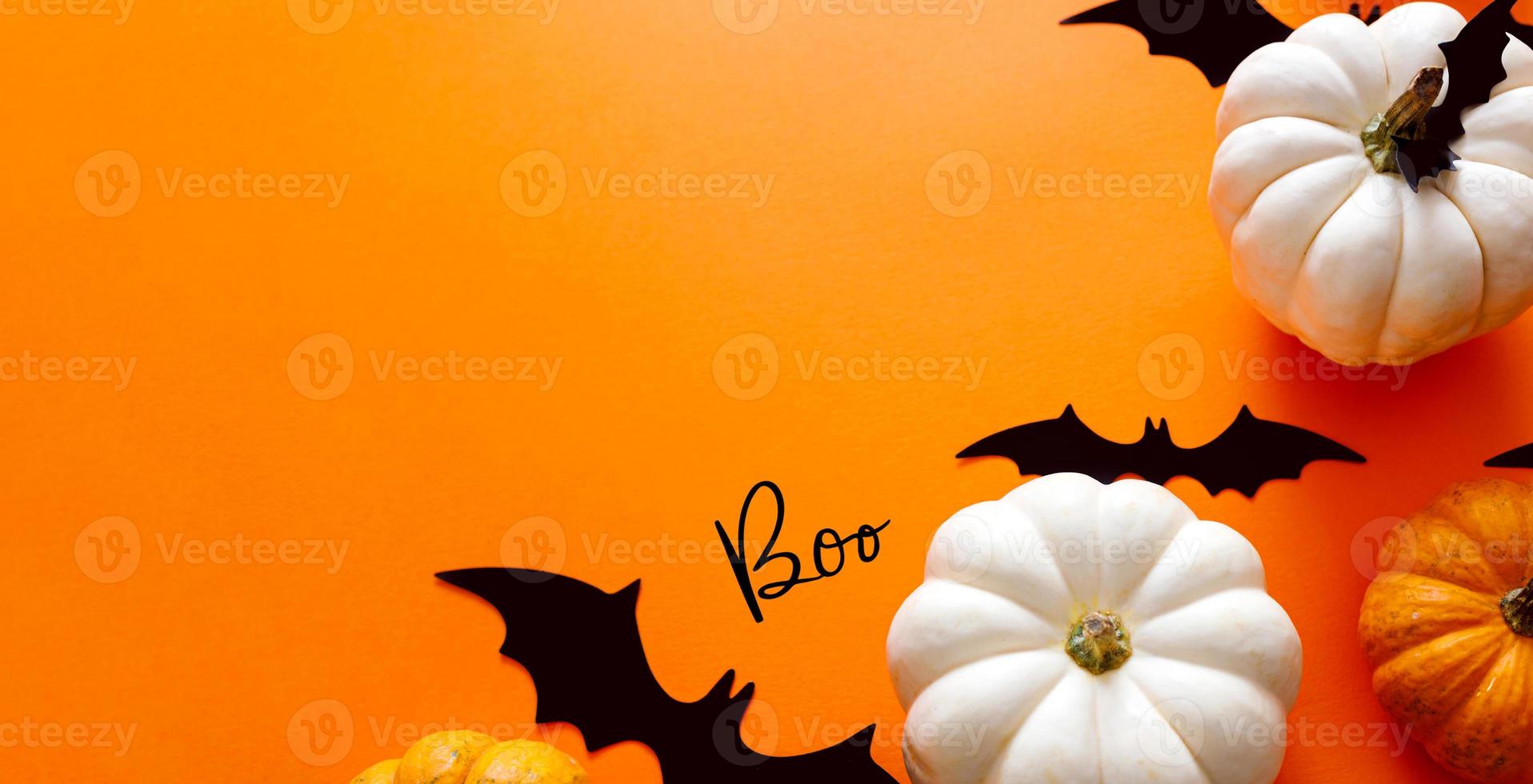 Halloween flat lay composition of black paper bats fand pumpkins on orange background. Halloween concept. photo