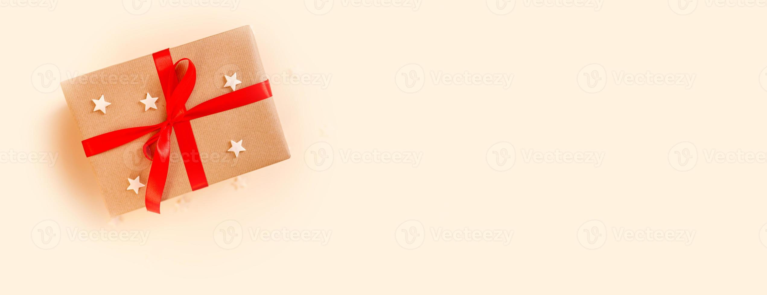 Christmas gift box with red bow on beige background. Holiday concept, New year presents. photo