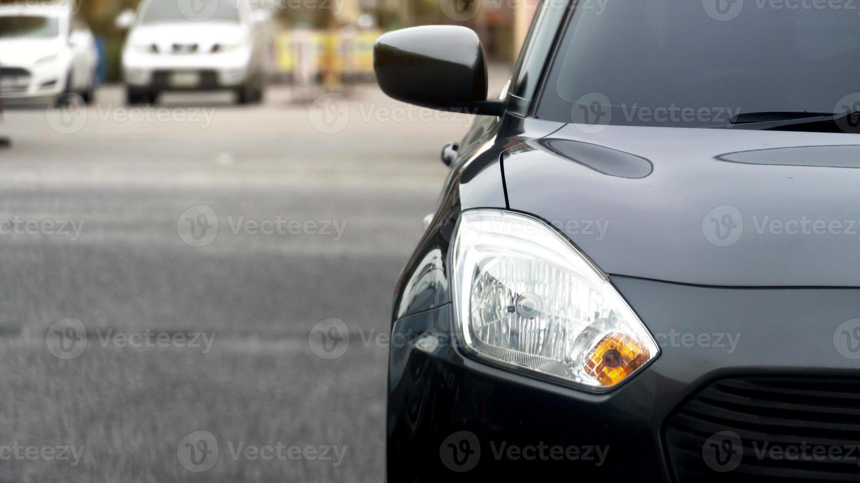 Front of black car on the road with blurred of other cars in the back photo