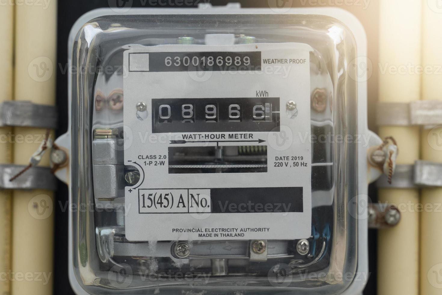 Front view of Power meter of Thailand attached to outdoor power pole. with yellow pipe beside of volt meter. photo