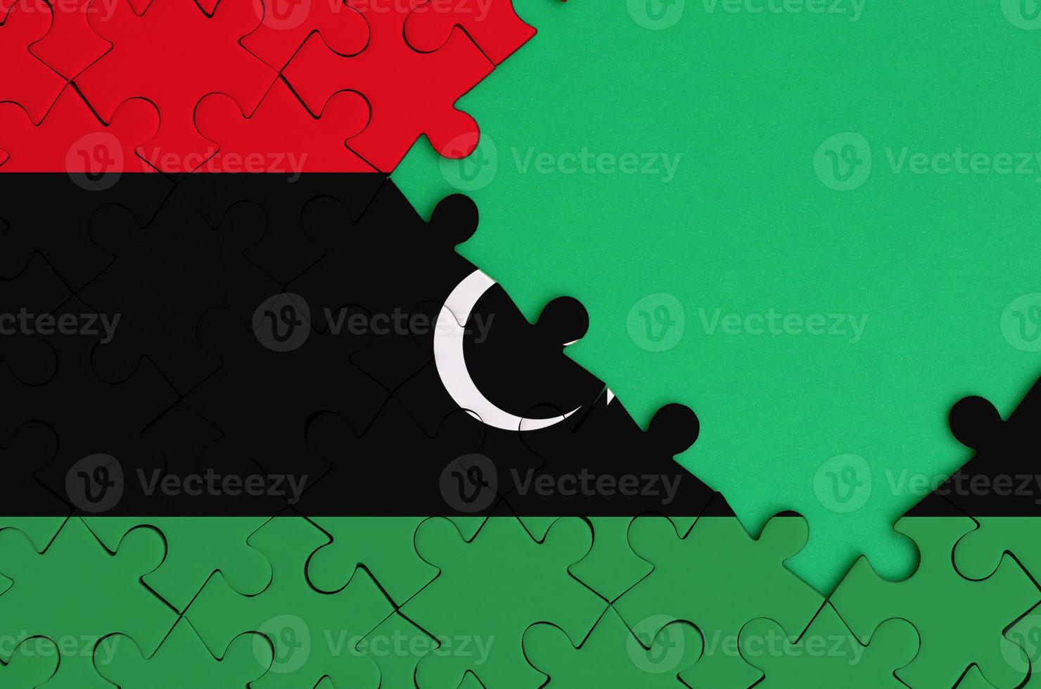 Libya flag  is depicted on a completed jigsaw puzzle with free green copy space on the right side photo