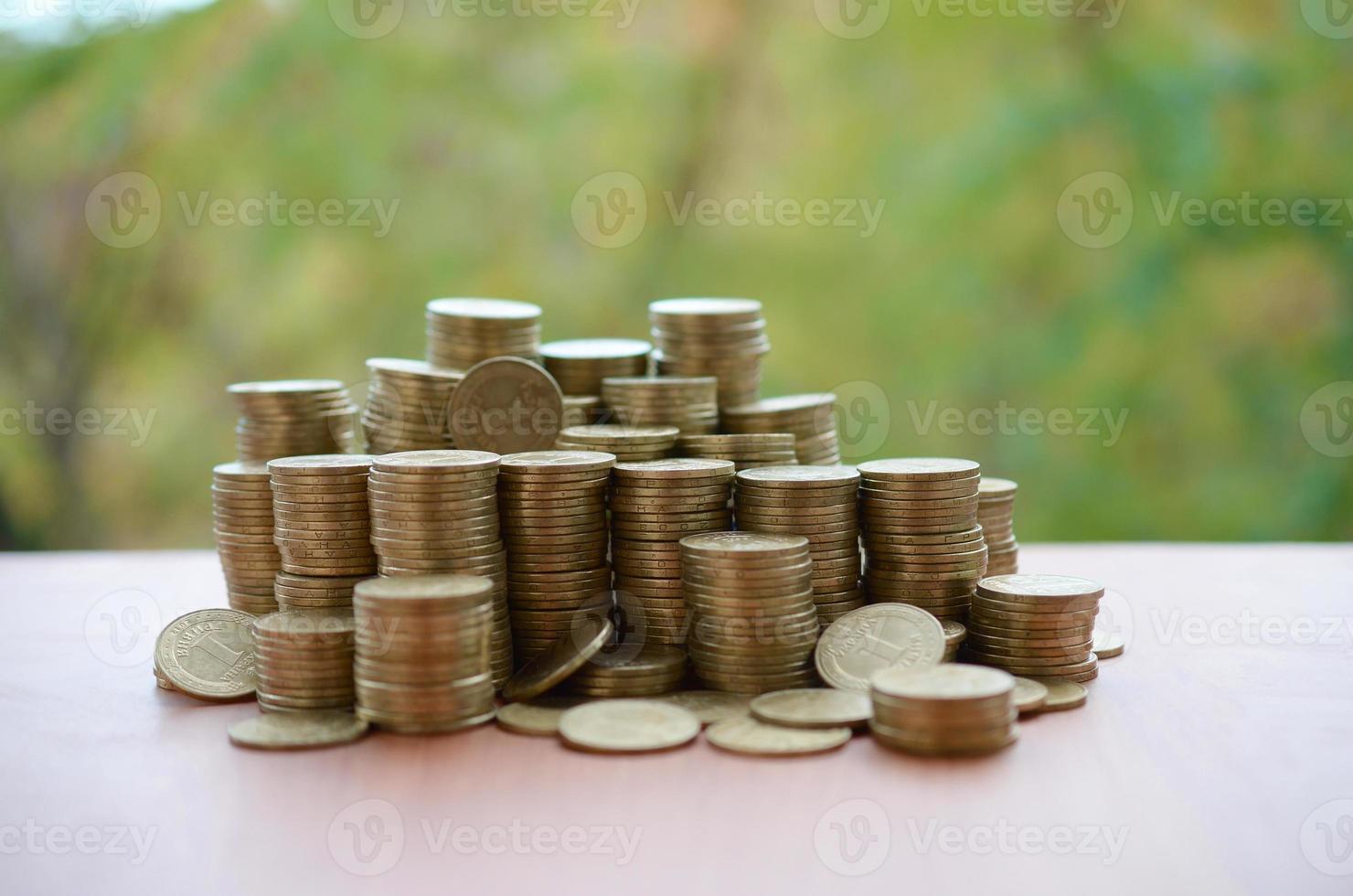 Big amount of shiny ukrainian old 1 hryvnia coin stacks close up on wooden table on green trees backdrop. The concept of business and rich life in Ukraine photo