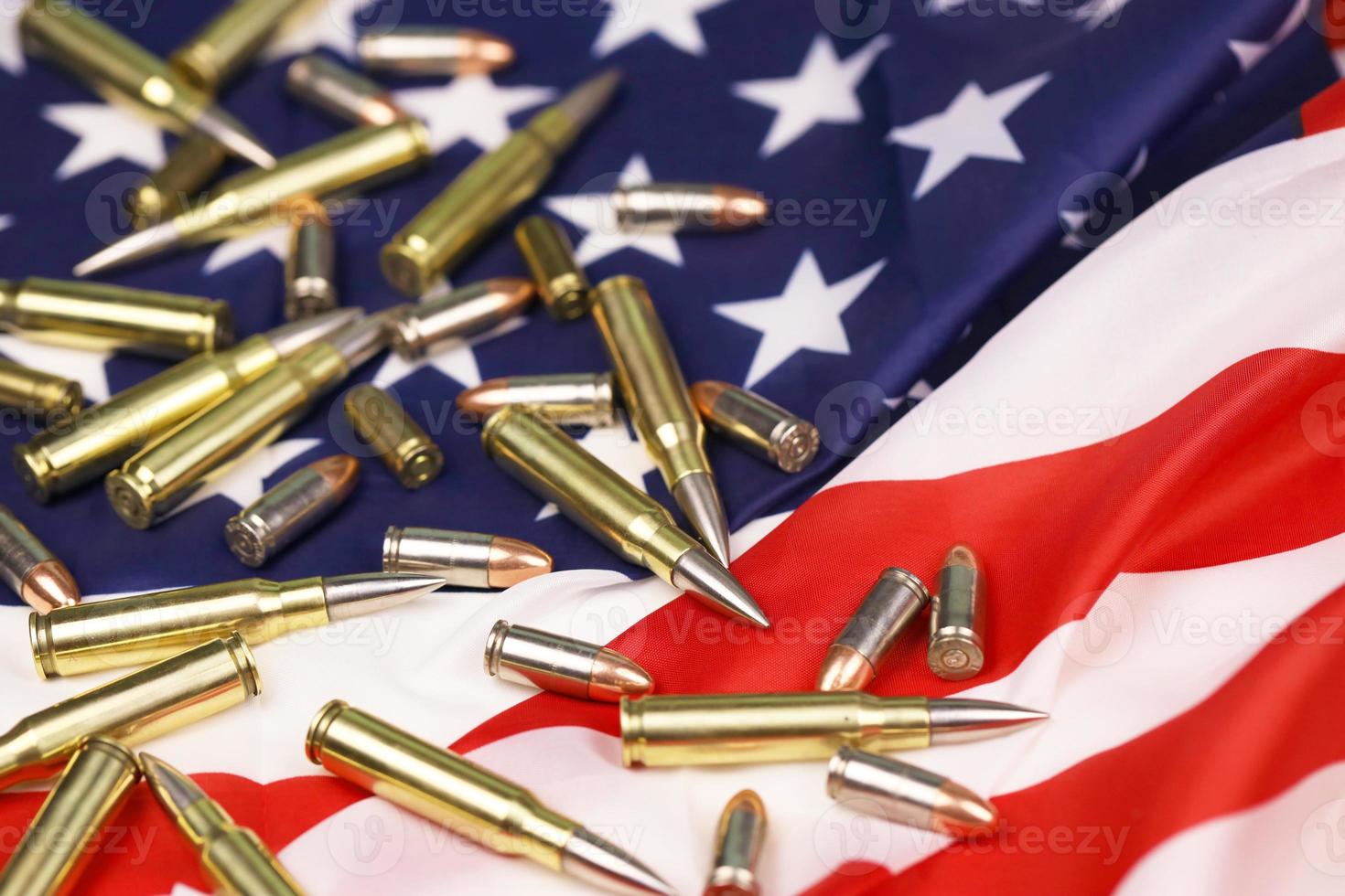 Many yellow 9mm and 5.56mm bullets and cartridges on United States flag. Concept of gun trafficking on USA territory or special ops photo