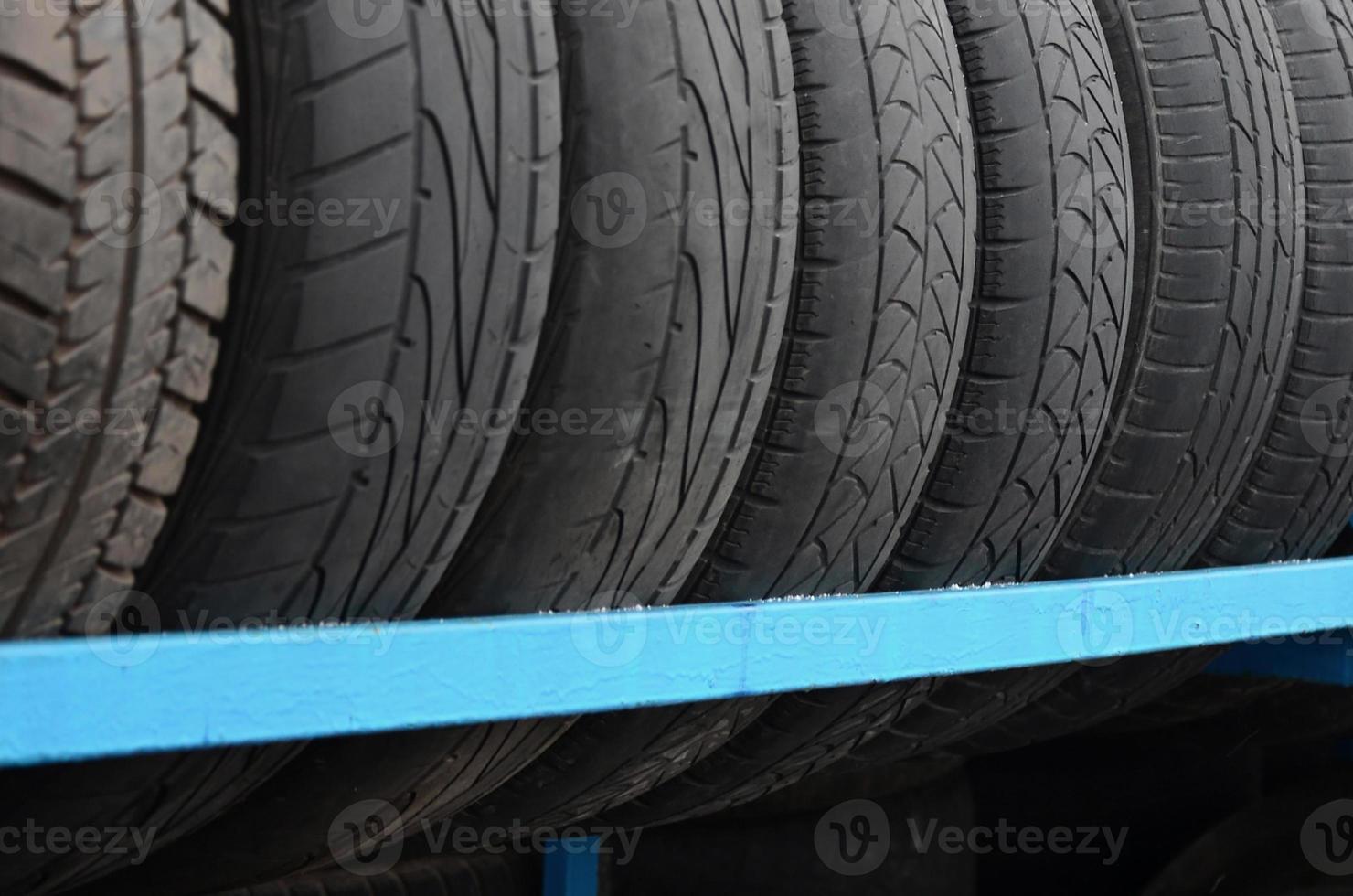 Rack with variety of car tires in automobile store. Many black tires. Tire stack background photo