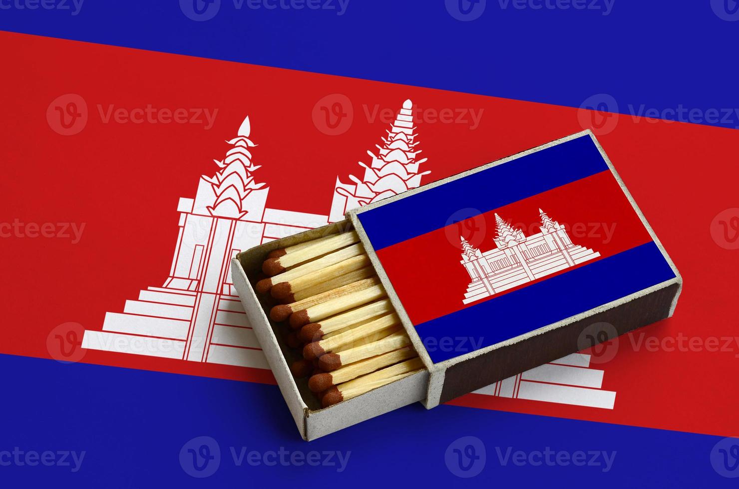 Cambodia flag  is shown in an open matchbox, which is filled with matches and lies on a large flag photo