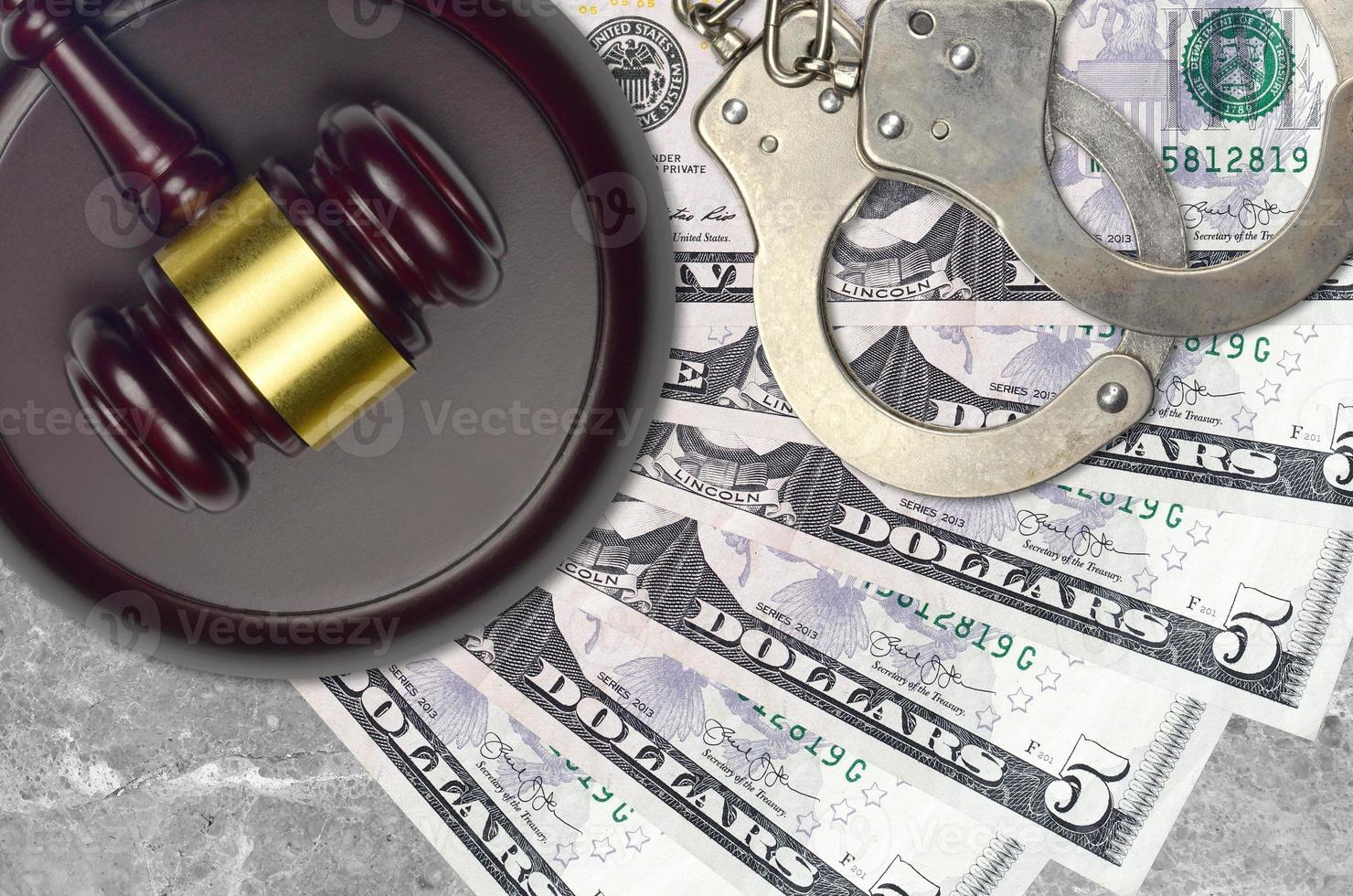 5 US dollars bills and judge hammer with police handcuffs on court desk. Concept of judicial trial or bribery. Tax avoidance photo