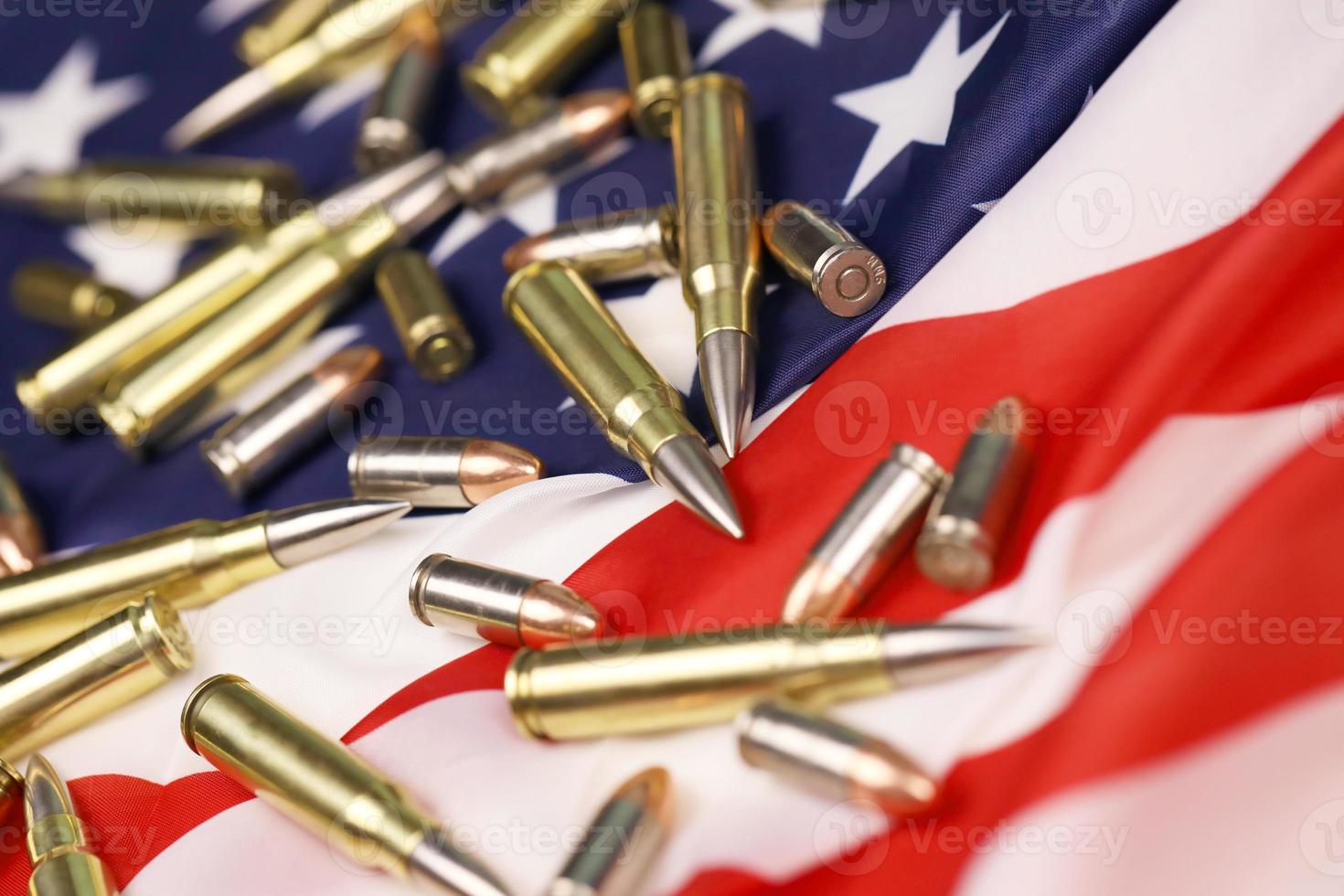 Many yellow 9mm and 5.56mm bullets and cartridges on United States flag. Concept of gun trafficking on USA territory or special ops photo