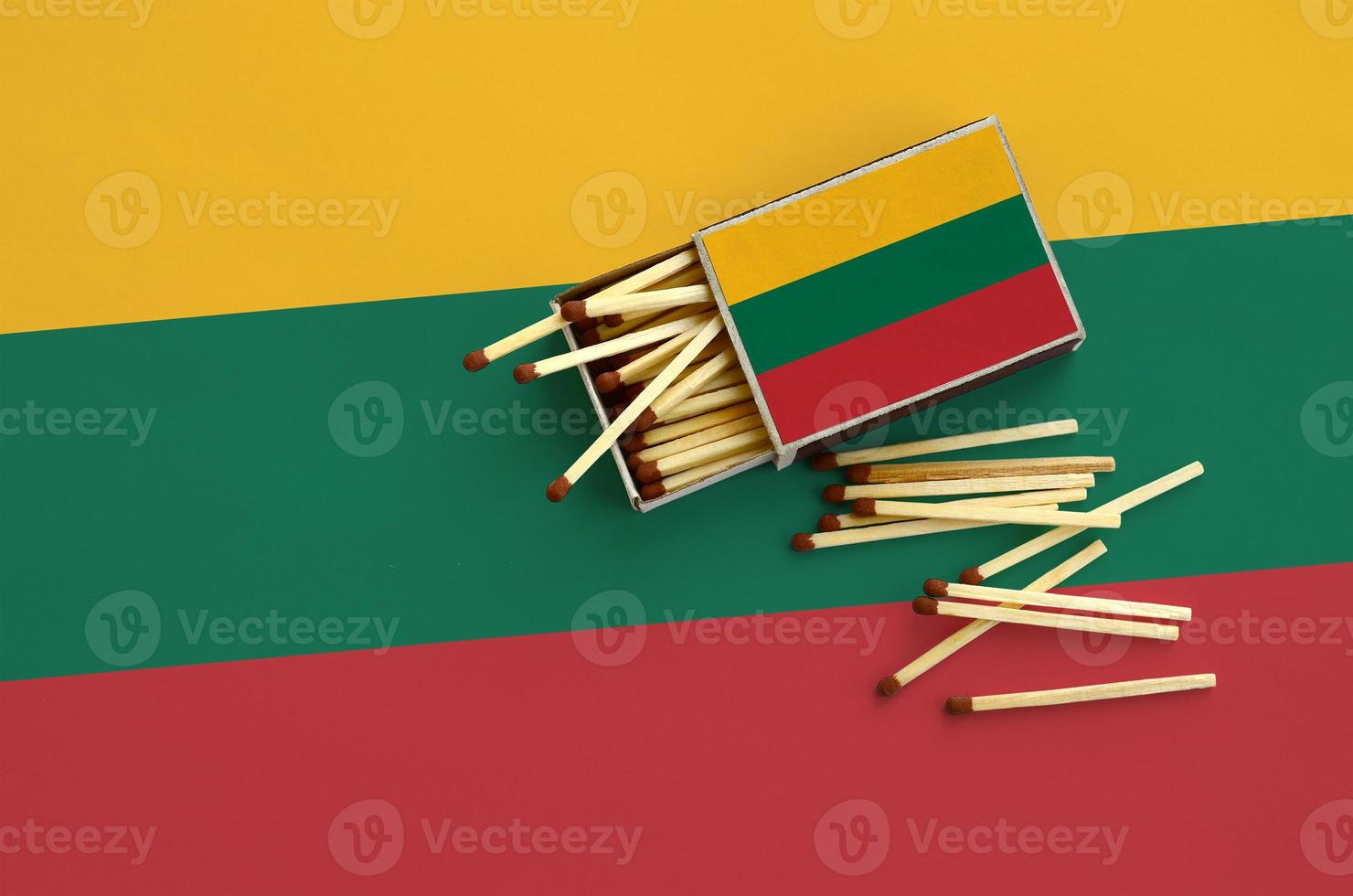 Lithuania flag  is shown on an open matchbox, from which several matches fall and lies on a large flag photo