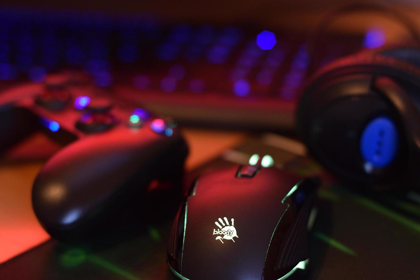 KHARKIV, UKRAINE - MAY 2, 2021 Gamesir g3s video game controller and Bloody p93 gaming mouse on office table with a4tech keyboard and headphones photo