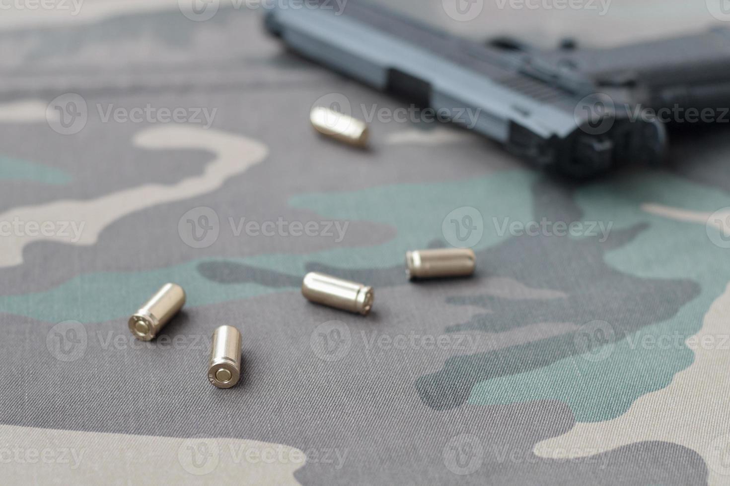 9mm bullets and pistol lie on camouflage green fabric. A set shooting range items or a self-defense kit photo