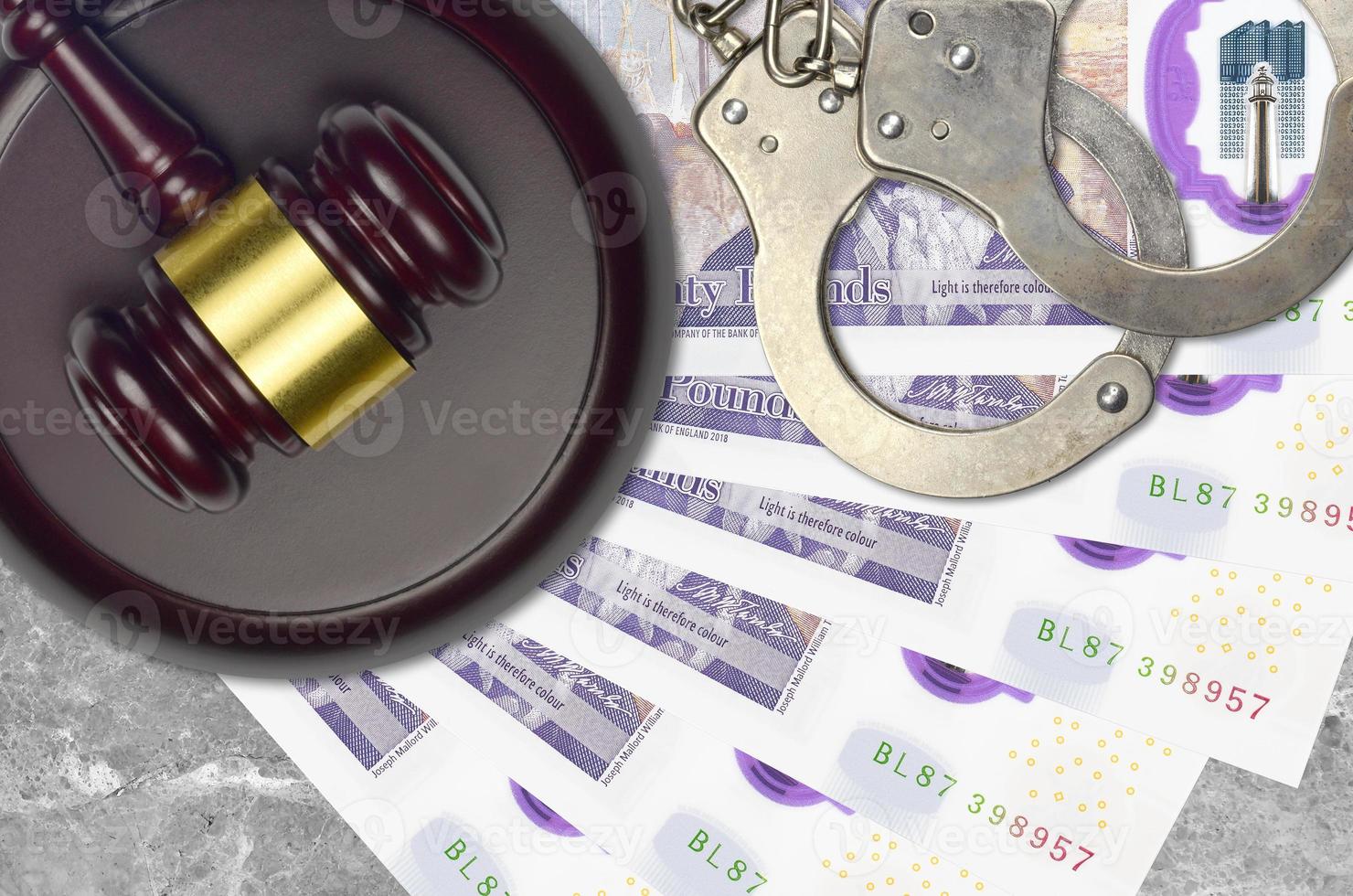 20 British pounds bills and judge hammer with police handcuffs on court desk. Concept of judicial trial or bribery. Tax avoidance photo