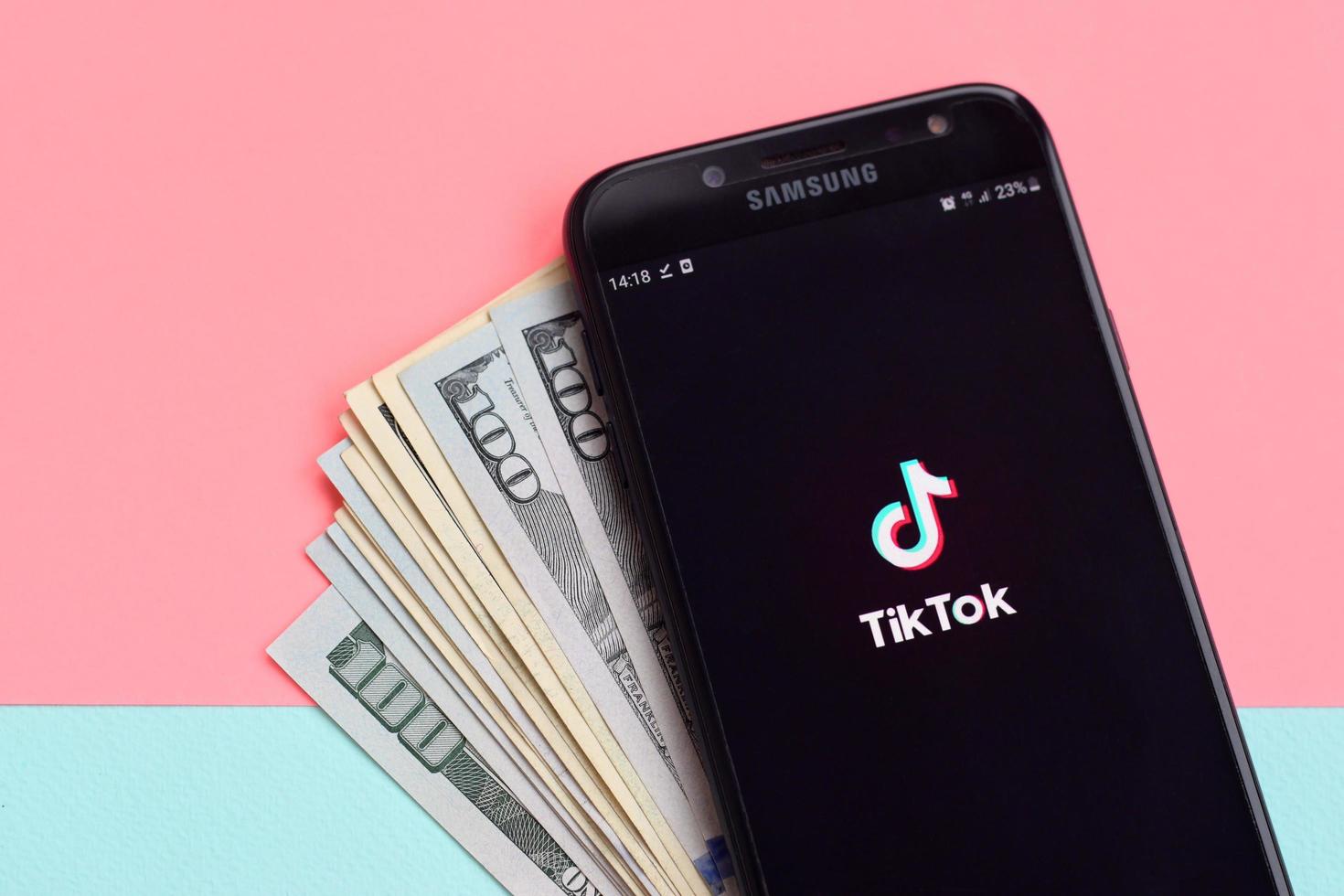 kharkiv, ucrania - 2 de mayo de 2021 aplicación tiktok en la pantalla del teléfono inteligente samsung y billetes de dólar. tiktok es un popular servicio de redes sociales para compartir videos propiedad de bytedance foto