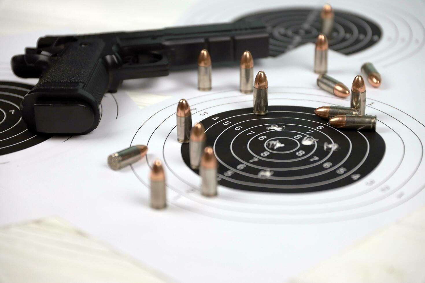 Gun and many bullets shooting targets on white table in shooting range polygon. Training for aiming and shooting photo