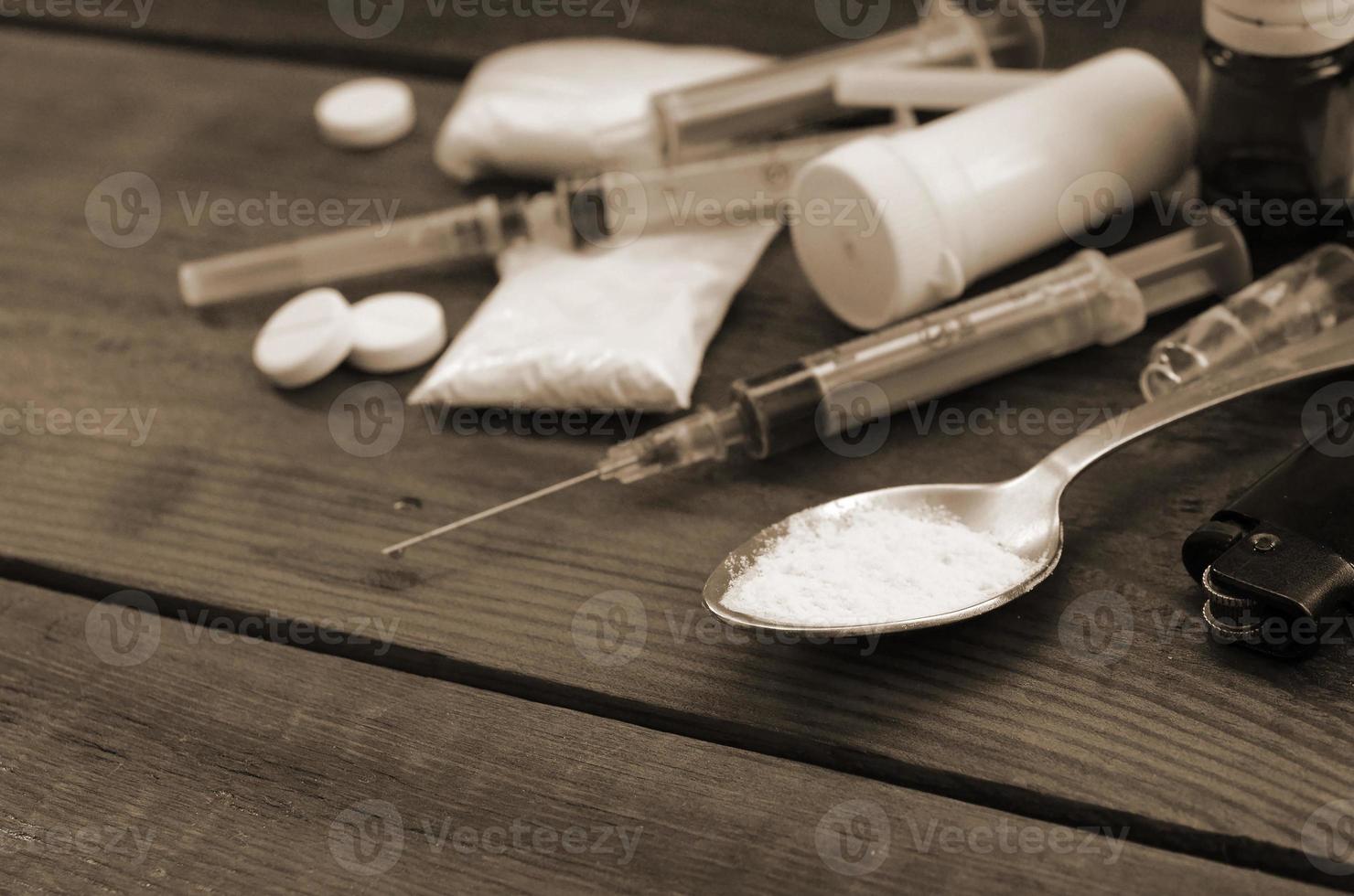 A lot of narcotic substances and devices for the preparation of drugs lie on an old wooden table photo