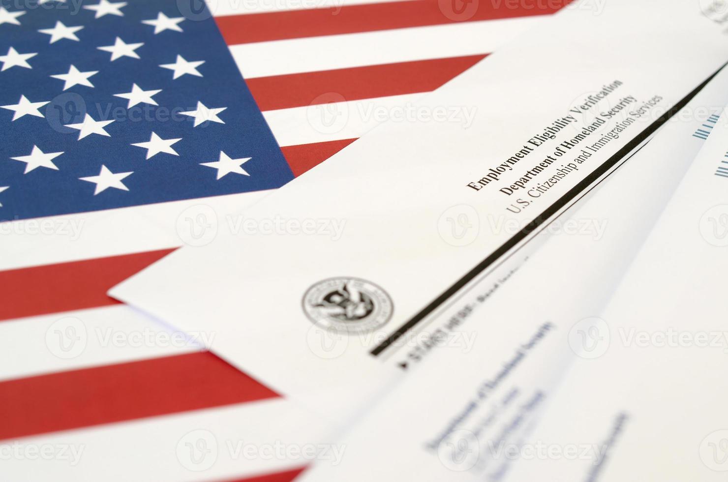 I-9 Employment Eligibility Verification blank form lies on United States flag with envelope from Department of Homeland Security photo