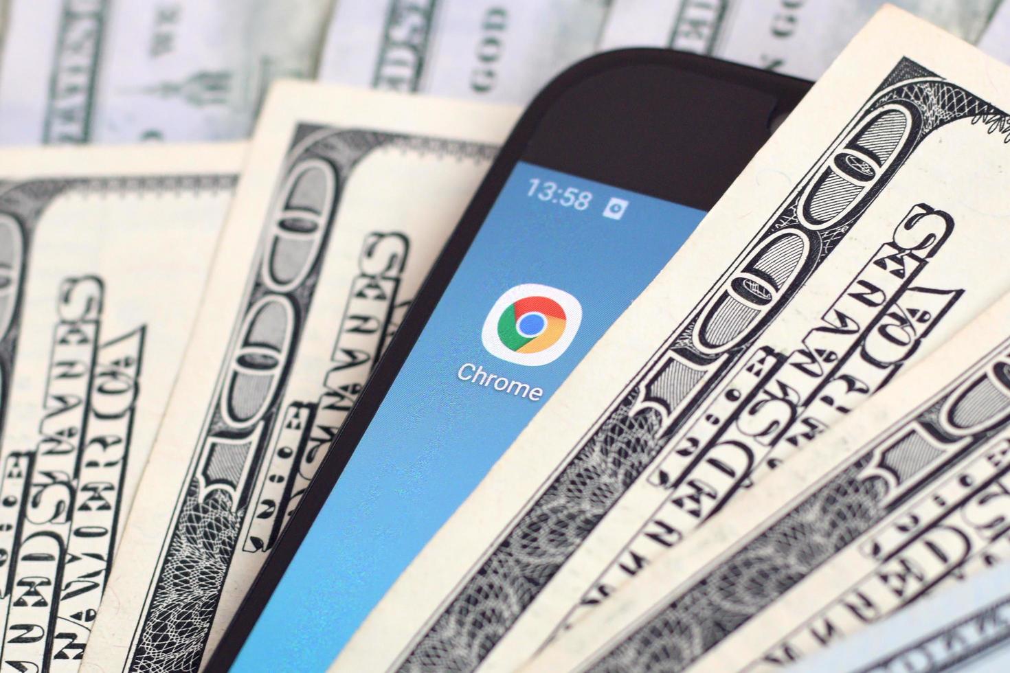 KHARKIV, UKRAINE - MAY 2, 2021 Smartphone screen with Google chrome app and lot of hundred dollar bills. Business and social networking concept photo