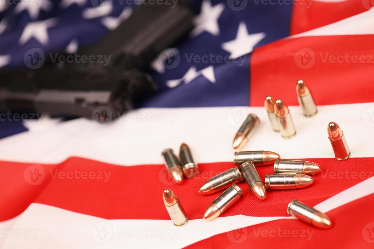 Many yellow 9mm bullets and gun on United States flag. Concept of gun trafficking on USA territory or shooting range photo