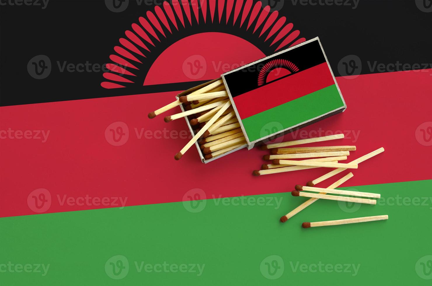 Malawi flag  is shown on an open matchbox, from which several matches fall and lies on a large flag photo