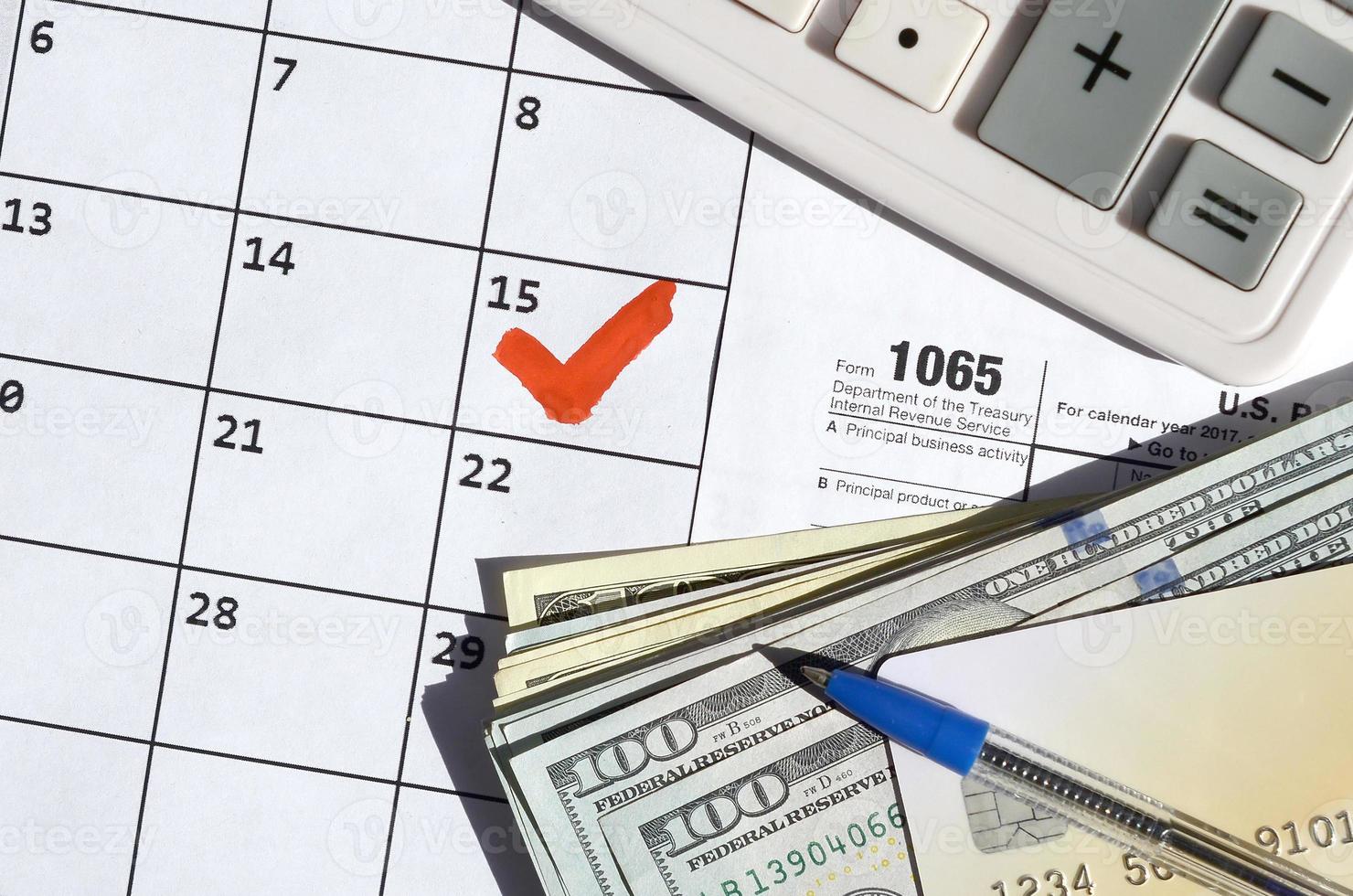 1065 Return of partnership income blank with dollar bills, calculator and pen on calendar page with marked 15th April photo