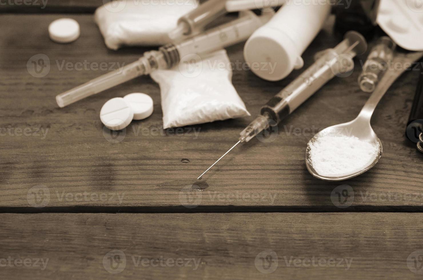 A lot of narcotic substances and devices for the preparation of drugs lie on an old wooden table photo