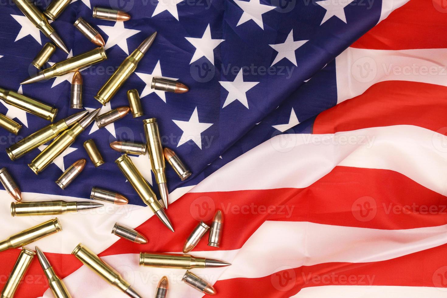 Many yellow 9mm and 5.56mm bullets and cartridges on United States flag. Concept of gun trafficking on USA territory or special ops photo