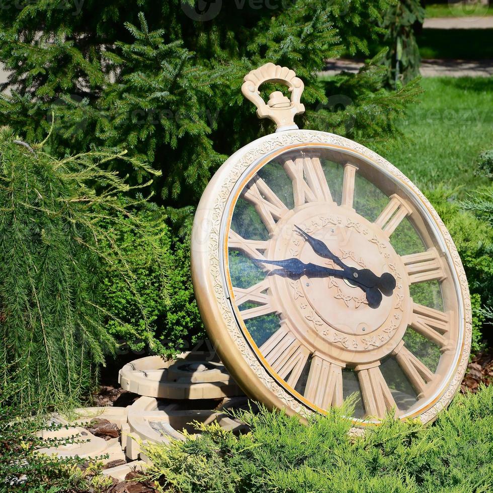 Street clock in a park under branches of trees close up photo