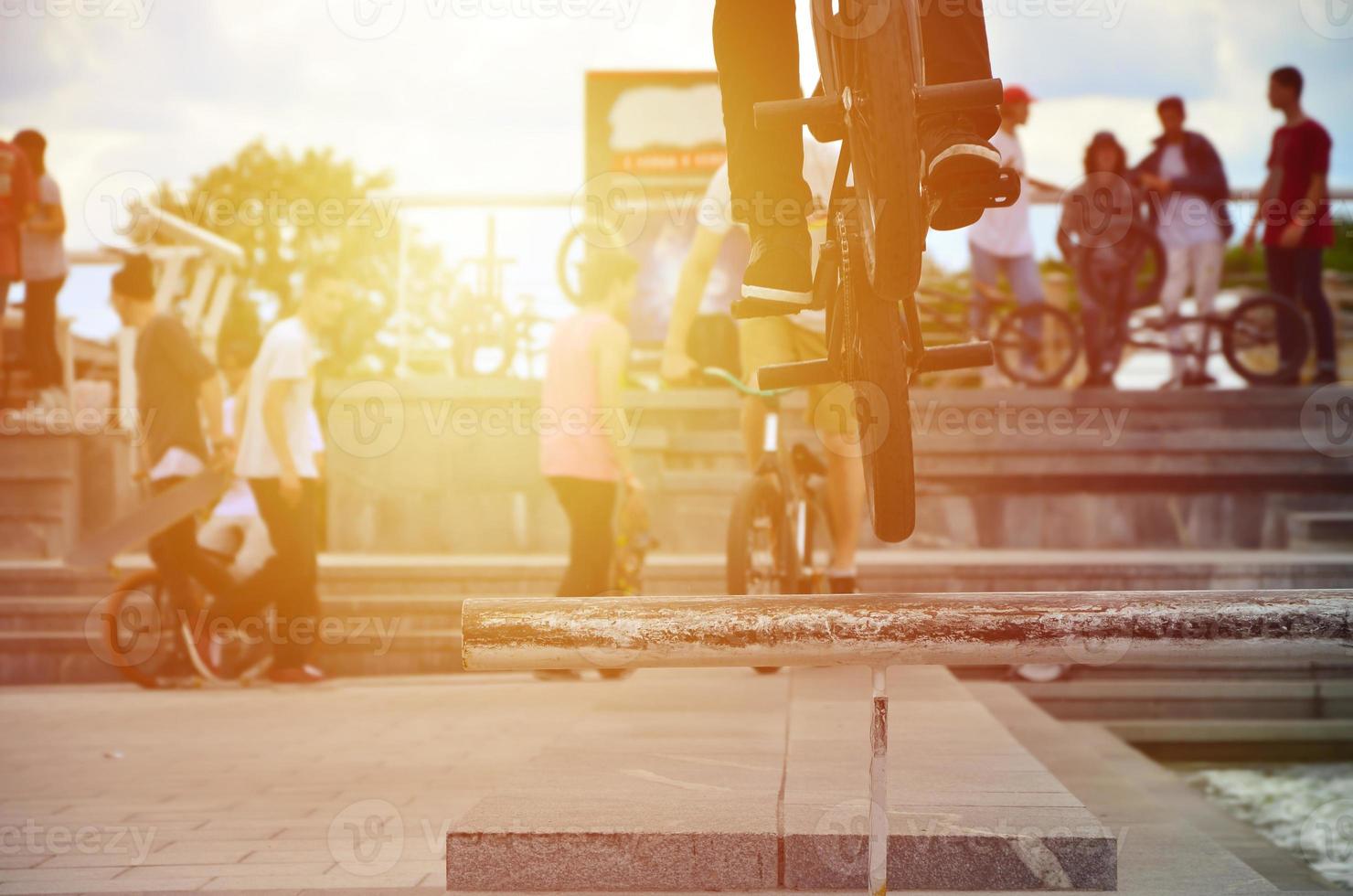 A cyclist jumps over a pipe on a BMX bike. A lot of people with bicycles in the background. Extreme sports concept photo