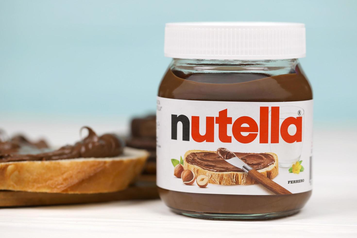 KHARKOV, UKRAINE - DECEMBER 27, 2020 Nutella glass can and spread on freshly baked bread. Nutella is manufactured by Italian company Ferrero first introduced in 1964 photo