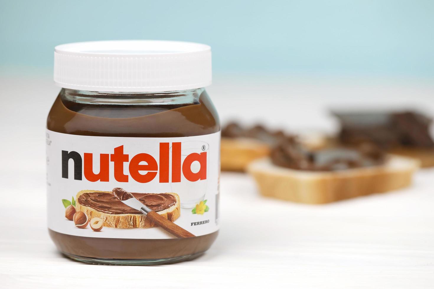 KHARKOV, UKRAINE - DECEMBER 27, 2020 Nutella glass can and spread on freshly baked bread. Nutella is manufactured by Italian company Ferrero first introduced in 1964 photo