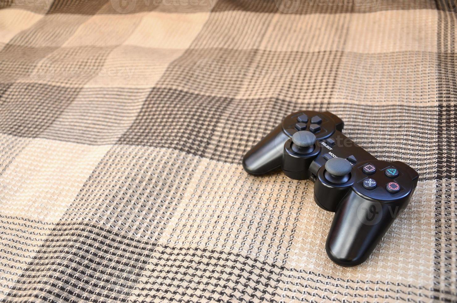 Video game controller lies on a checkered plaid photo