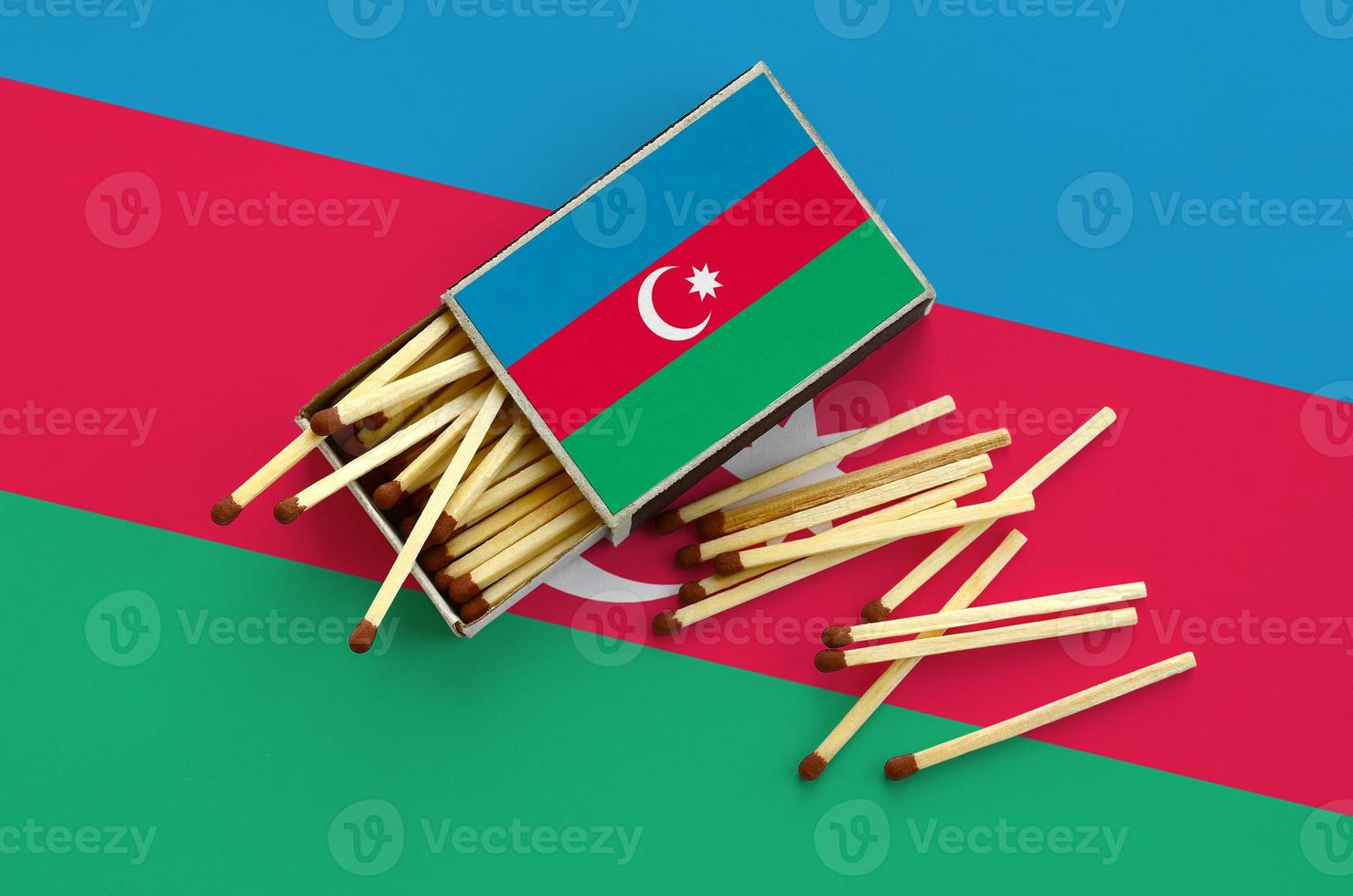 Azerbaijan flag  is shown on an open matchbox, from which several matches fall and lies on a large flag photo