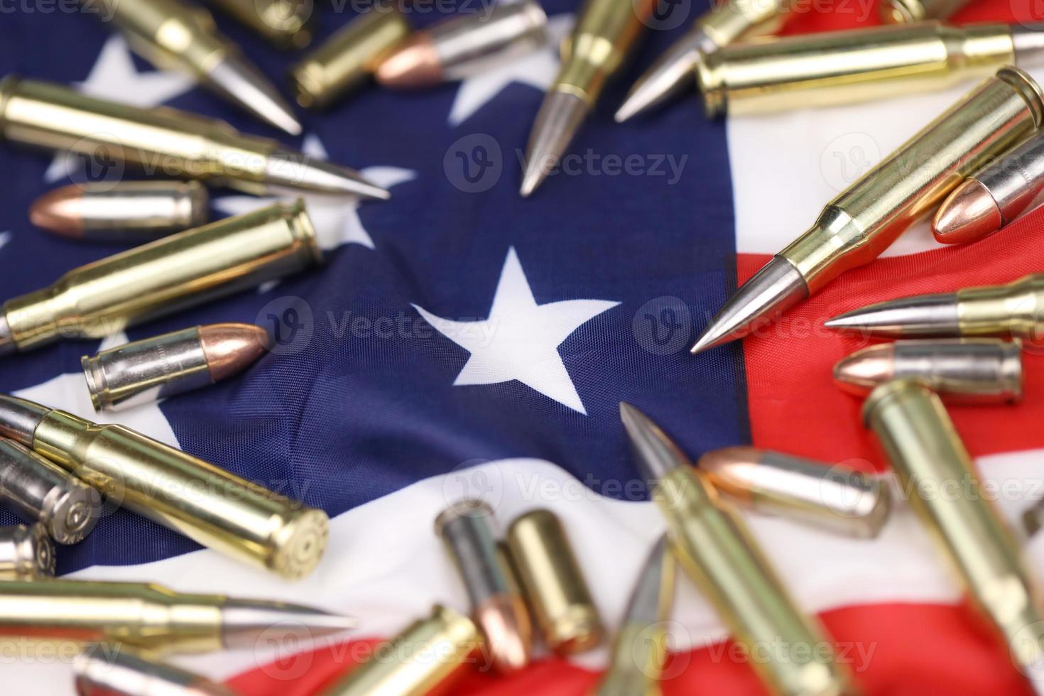 Many yellow 9mm and 5.56mm bullets and cartridges on United States flag. Concept of gun trafficking on USA territory or special ops photo