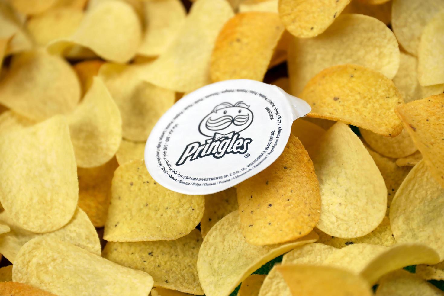 KHARKIV, UKRAINE - MAY 02, 2021 Pringles logo on paper membrane on many orange Pringles potato snack chips. Pringles is a brand of potato snack chips owned by Kellogg Company photo