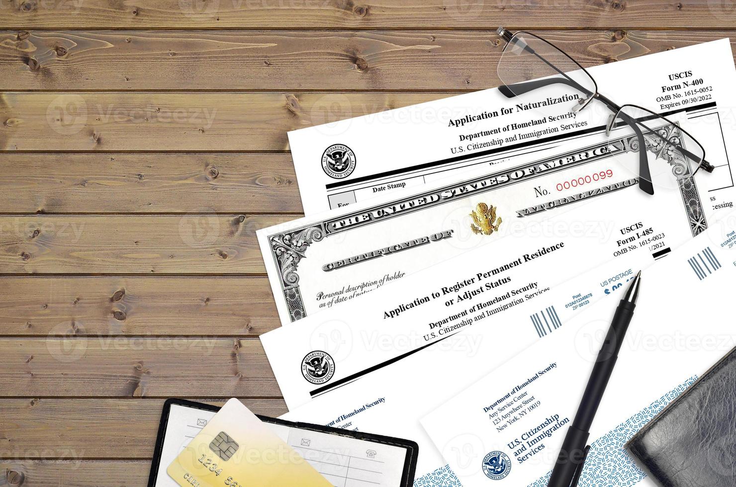 USCIS form I-485 Application to register permanent residence or adjust status and N-400 Application for naturalization with Certificate of naturalization lies on office table photo