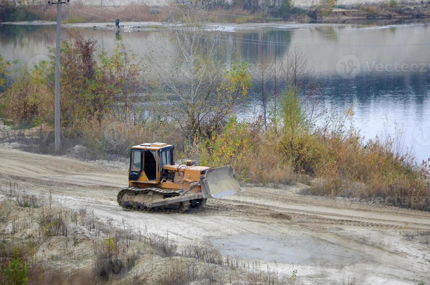 agregado de cantera con maquinaria pesada. Excavadora de oruga con retroexcavadora que conduce a la cantera del sitio de construcción foto