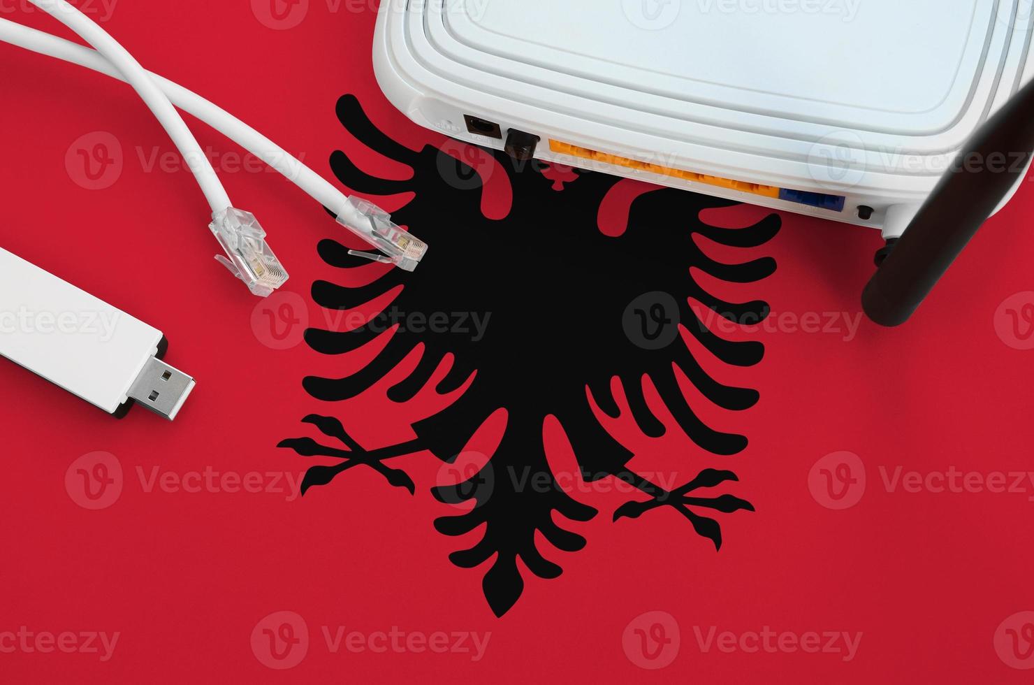 Albania flag depicted on table with internet rj45 cable, wireless usb wifi adapter and router. Internet connection concept photo