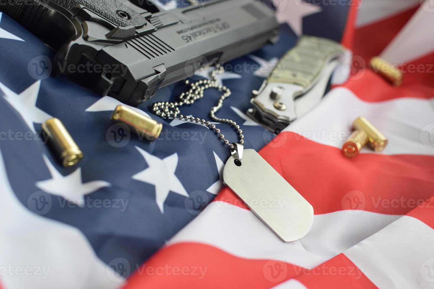 token de etiqueta de perro del ejército con balas de 9 mm y pistola en la bandera doblada de los estados unidos foto