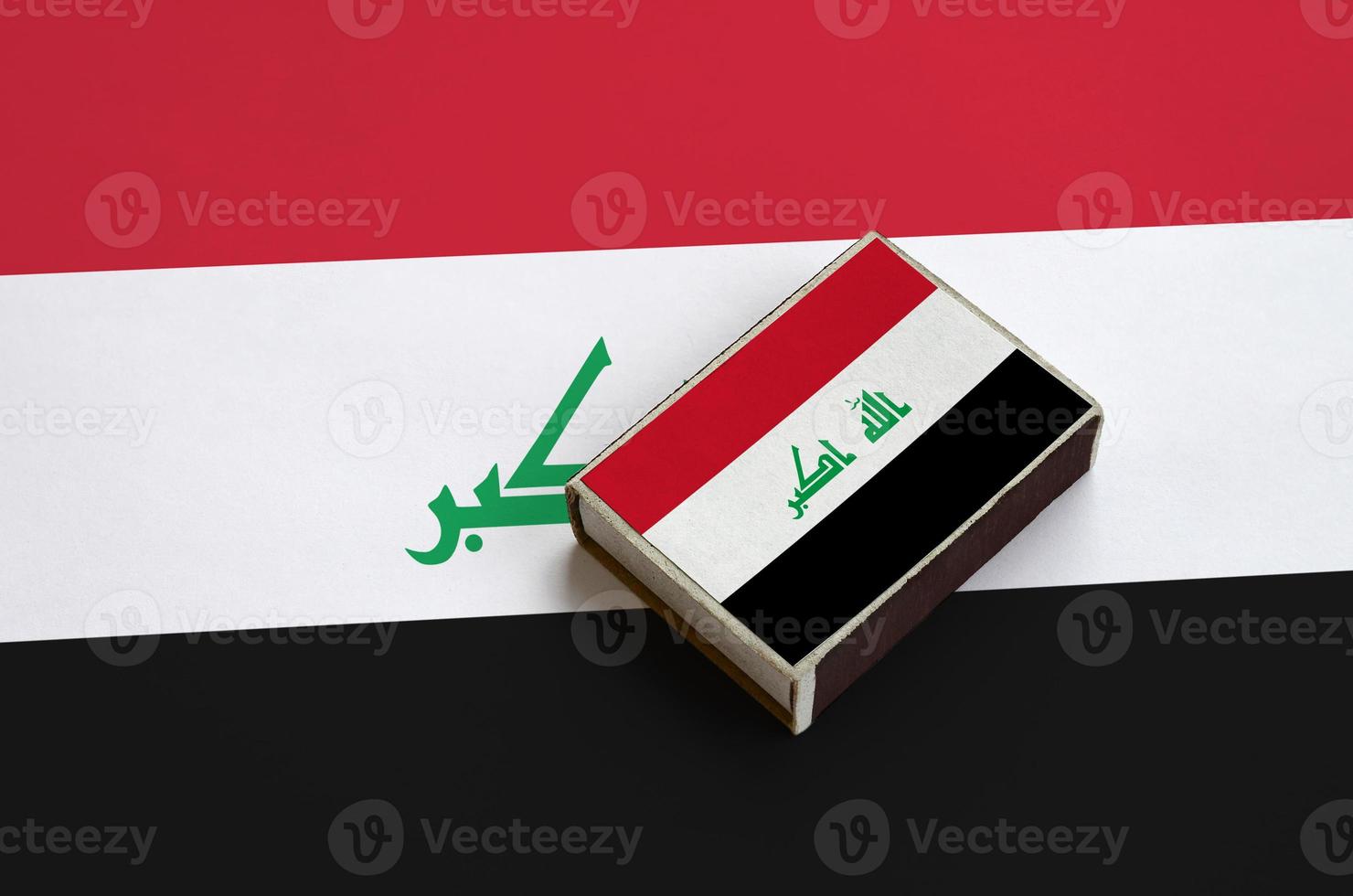 Iraq flag  is pictured on a matchbox that lies on a large flag photo