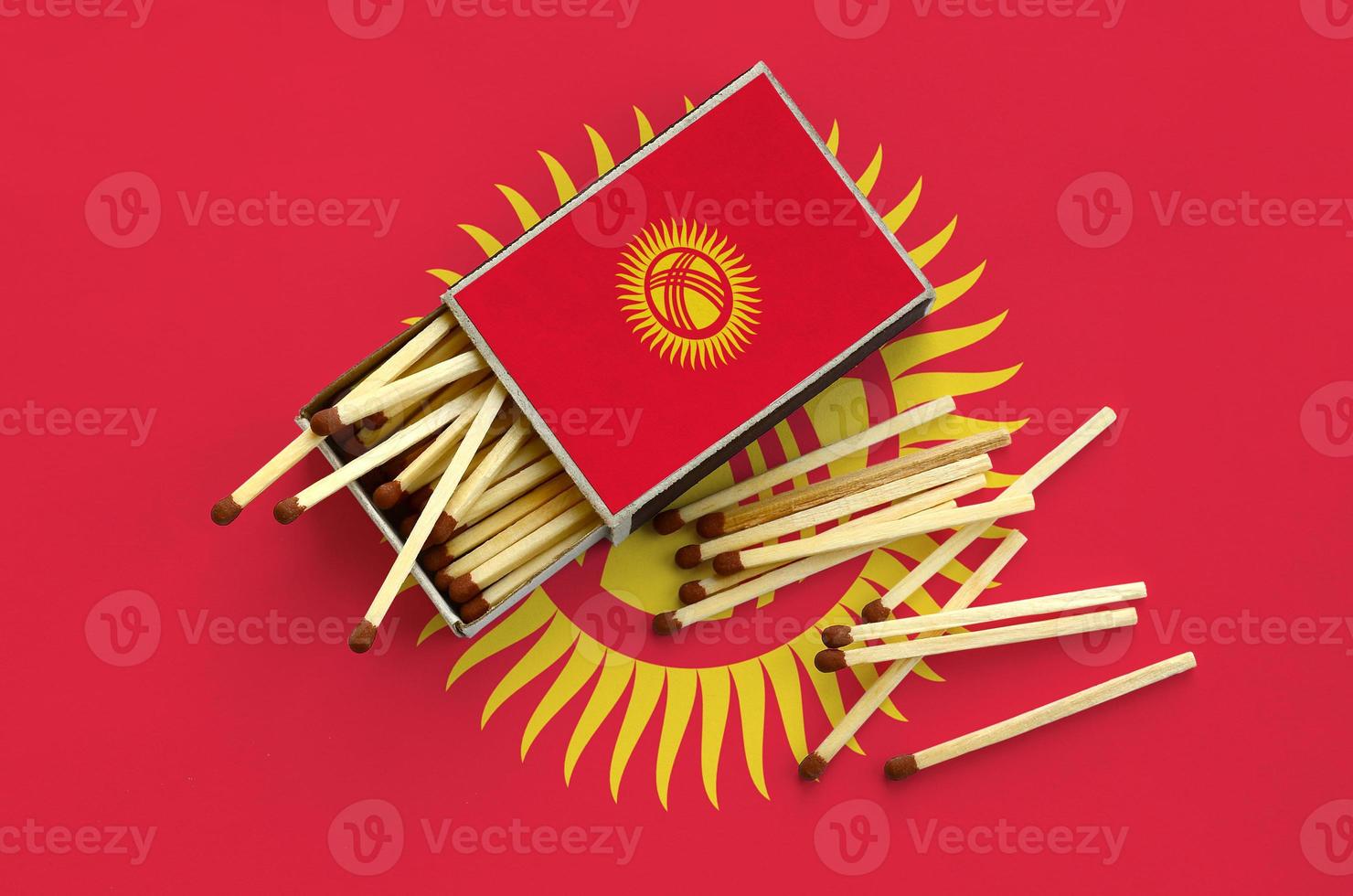 Kyrgyzstan flag  is shown on an open matchbox, from which several matches fall and lies on a large flag photo