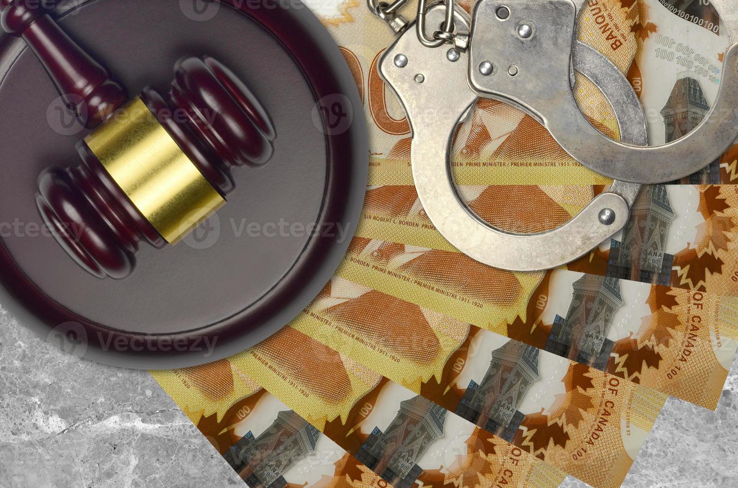 100 Canadian dollars bills and judge hammer with police handcuffs on court desk. Concept of judicial trial or bribery. Tax avoidance photo