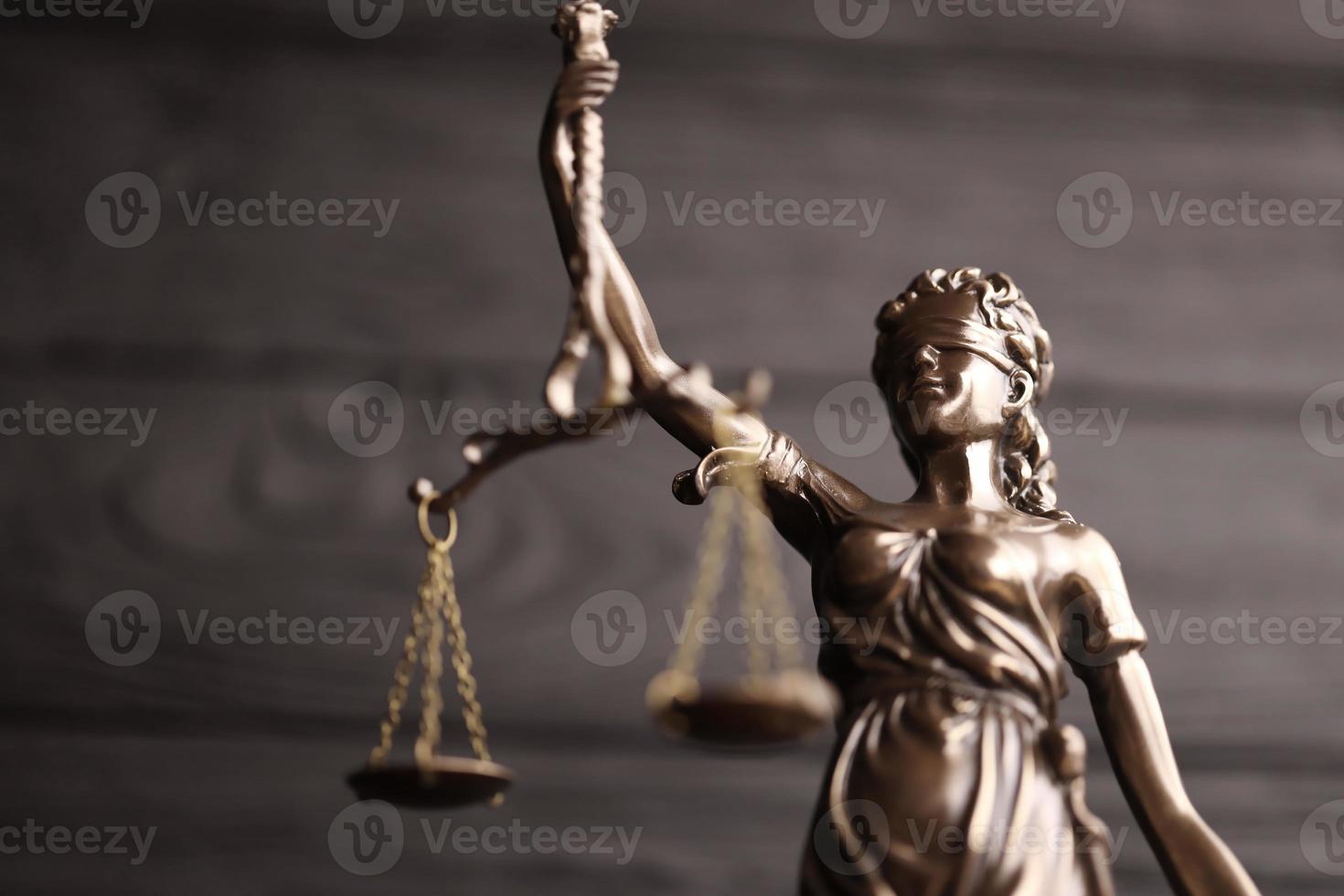 The Statue of Justice - lady justice or justitia the Roman goddess of Justice. Statue on black wooden wall. Concept of judicial trial, courtroom process and lawyers work photo