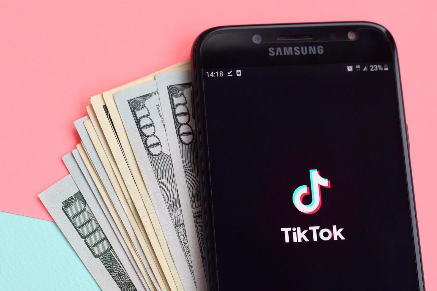 kharkiv, ucrania - 2 de mayo de 2021 aplicación tiktok en la pantalla del teléfono inteligente samsung y billetes de dólar. tiktok es un popular servicio de redes sociales para compartir videos propiedad de bytedance foto