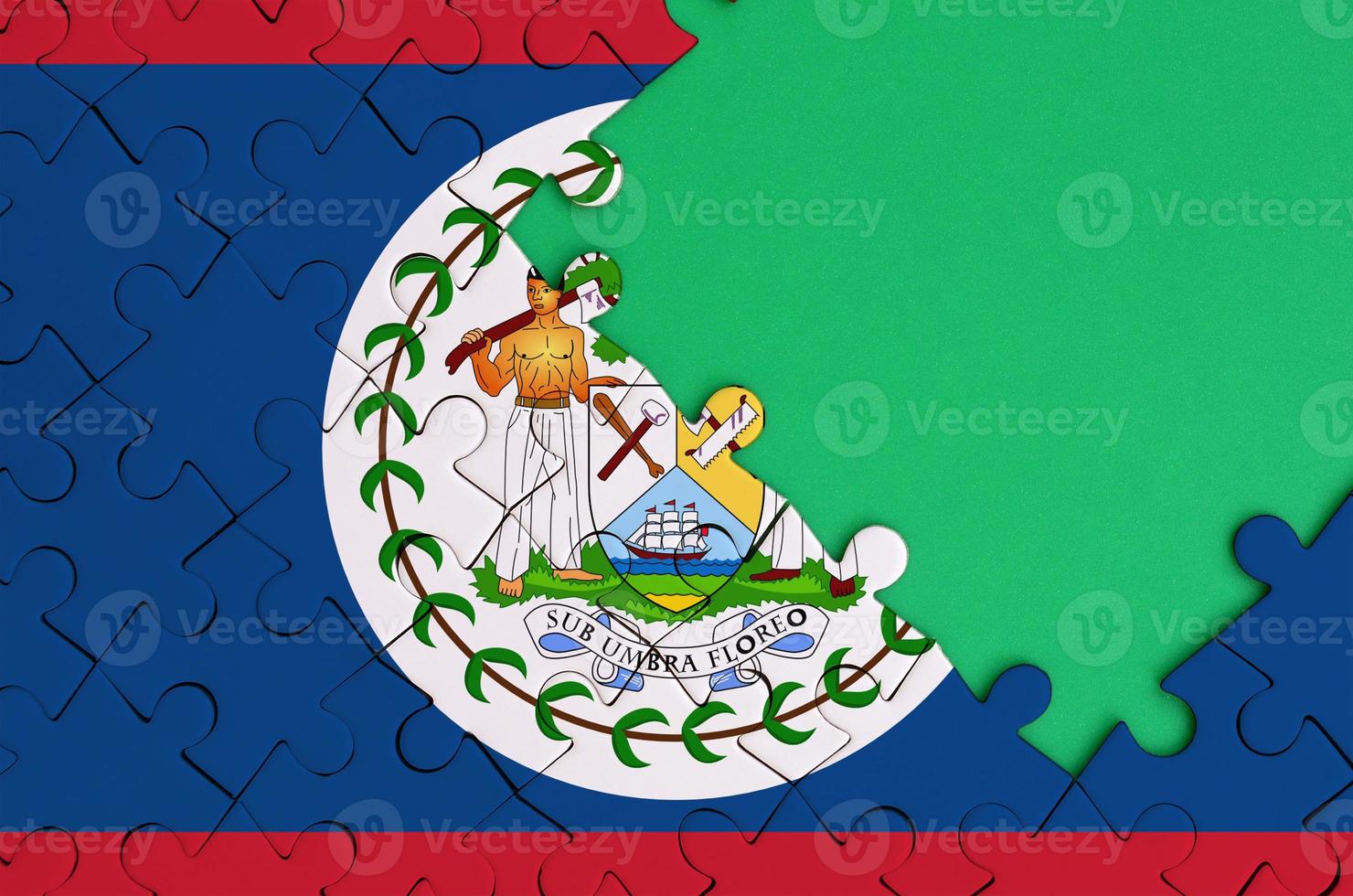 Belize flag  is depicted on a completed jigsaw puzzle with free green copy space on the right side photo