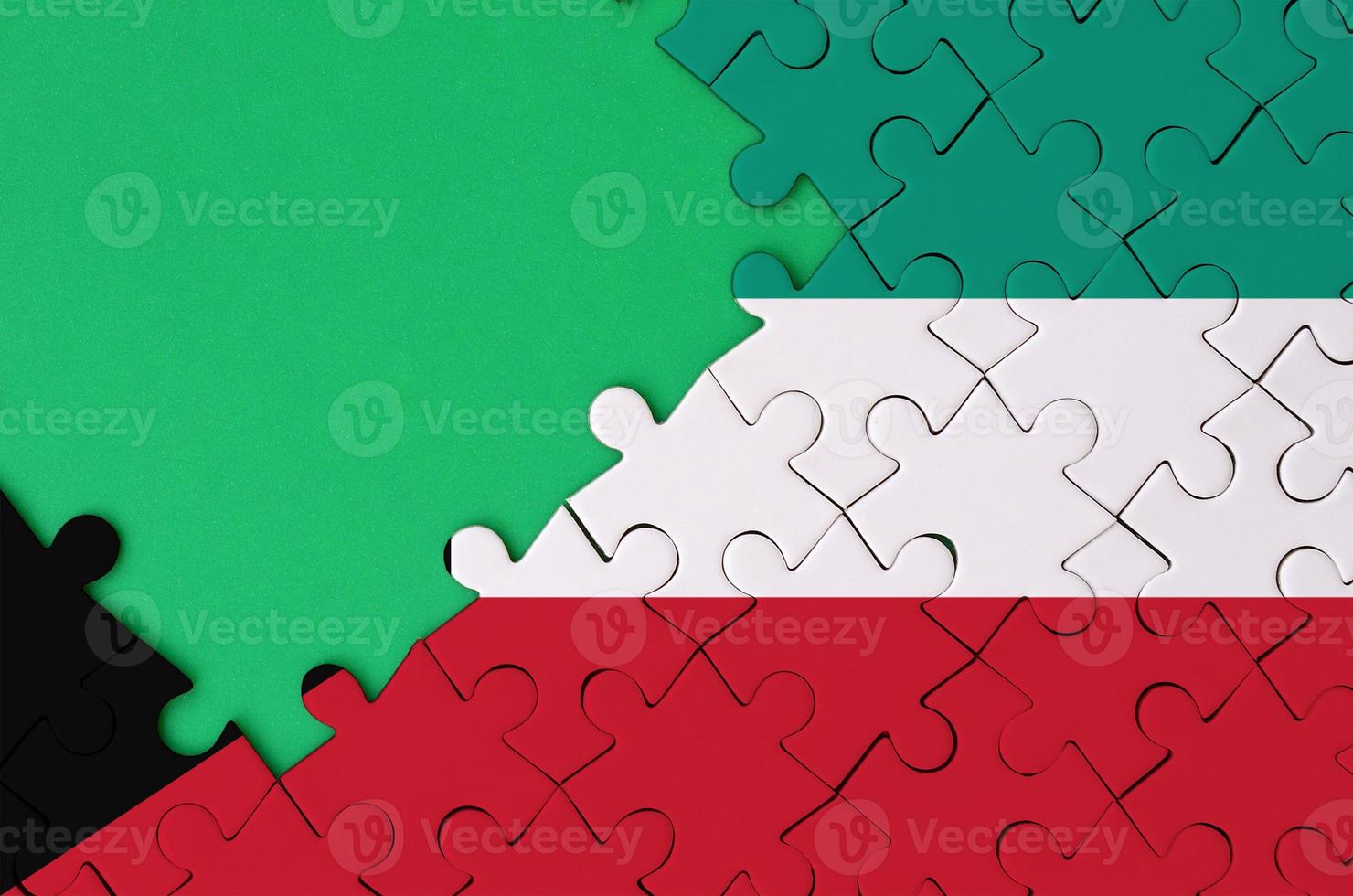 Kuwait flag  is depicted on a completed jigsaw puzzle with free green copy space on the left side photo
