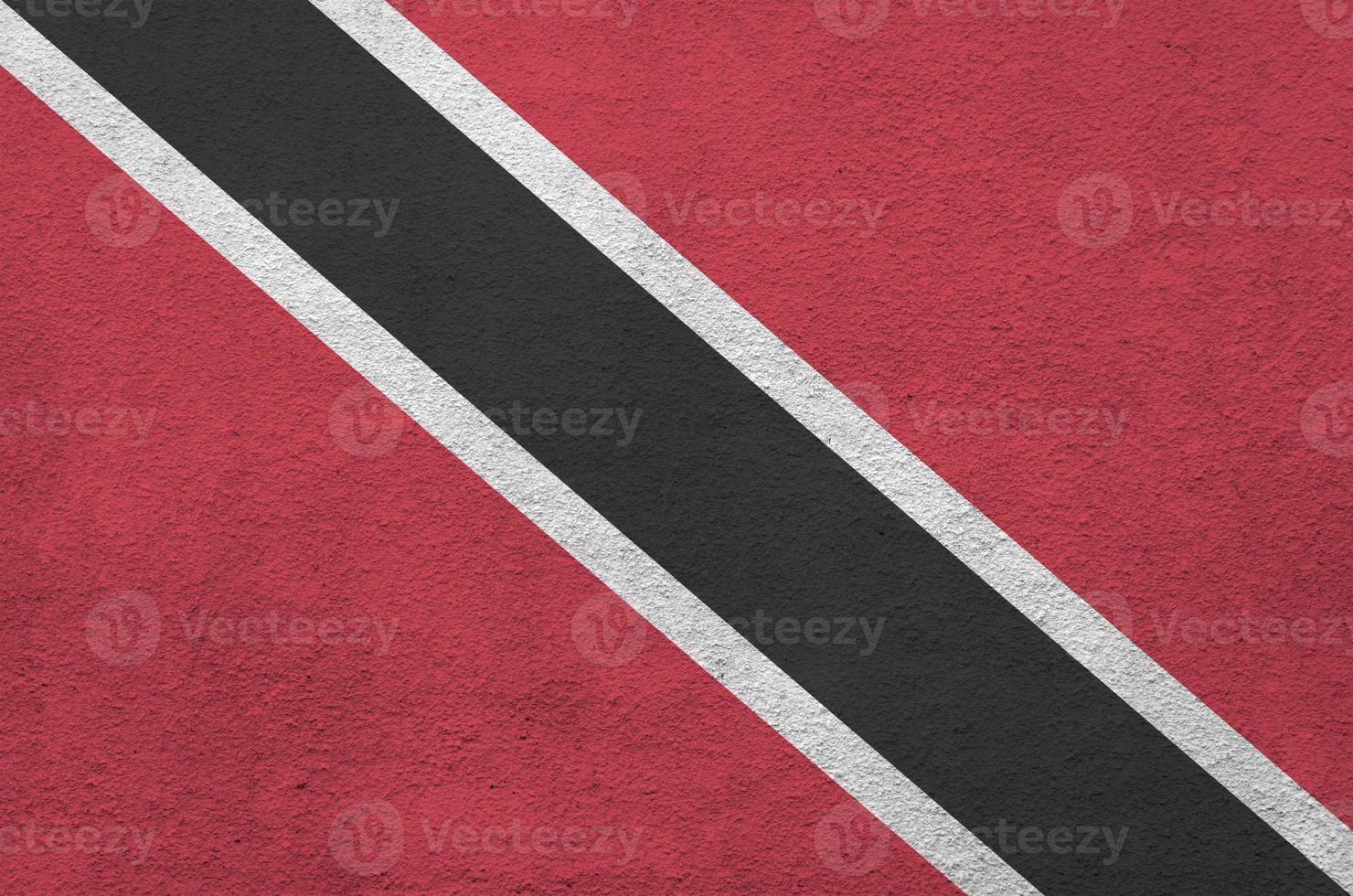 Trinidad and Tobago flag depicted in bright paint colors on old relief plastering wall. Textured banner on rough background photo