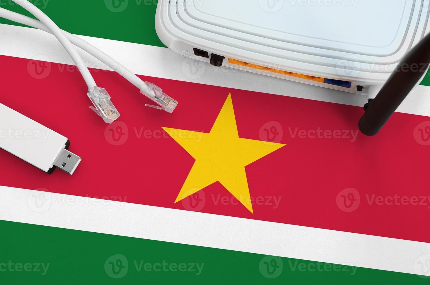 Suriname flag depicted on table with internet rj45 cable, wireless usb wifi adapter and router. Internet connection concept photo